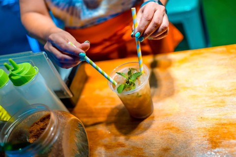 Close-up of the hands of a woman mixing mojito cocktail with straw