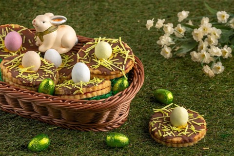 Easter biscuits in the shape of a nest with eggs in a basket in a meadow