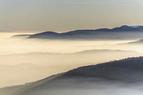 The mountains are shrouded in mist and the sky is a mixture of blue and white. The bleak atmosphere
