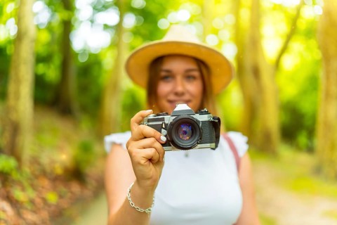 Portrait with selective focus on the camera in hands of a young female caucasian photographer in