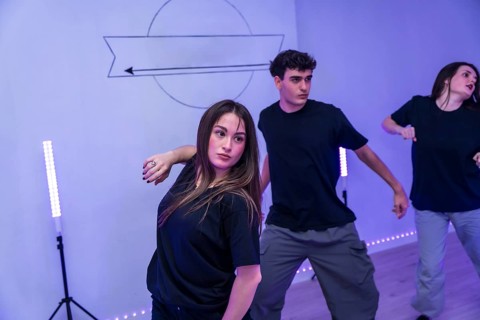 Group of young dancers practicing a modern choreography in a dance studio with neon lights