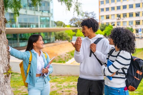 Three quarter length photo of three multi-ethnic friends talking standing together in the