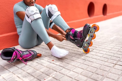 Cropped photo of part of an unrecognizable african woman putting on inline skates sitting on the