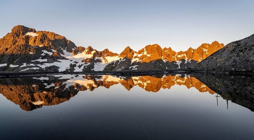 Rocky mountain peaks reflected in a small pond, mountain landscape with alpenglow at sunrise, at