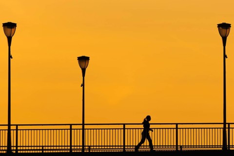 A jogger runs across the Old Bridge in Frankfurt am Main in the early morning shortly in front of