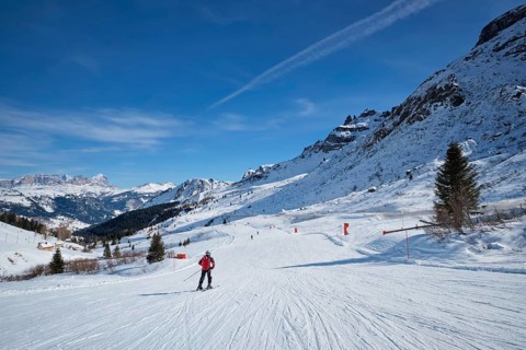 View of a ski resort piste with people skiing in Dolomites in Italy. Canazei, Italy, Europe