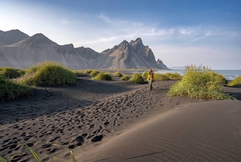Tourist on a sand dune, Black beach with volcanic sand, Sand beach, Dunes with grass, Stokksnes
