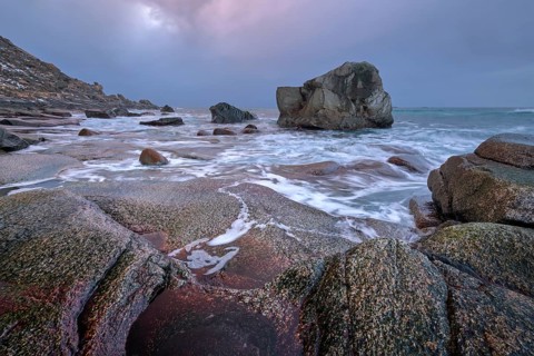 Rocks on beach of fjord of Norwegian sea in winter on sunset. Utakliev beach, Lofoten islands,