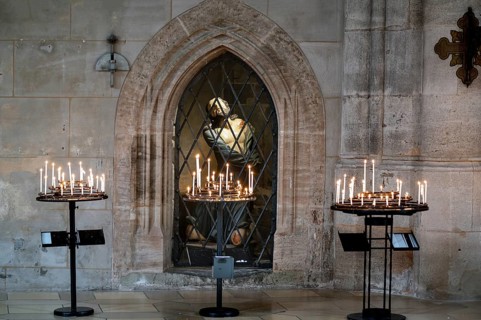 Sacrificial candles, behind them in the niche a figure of Jesus in the late Gothic hall church of