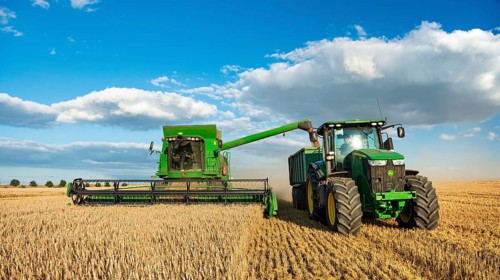 Combine harvester harvesting wheat and unloading grain onto tractor with trailer, endless