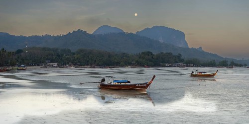 Before sunrise, longtail boats lie at low tide in the harbour at Sivalai Beach, Koh Mook Island,