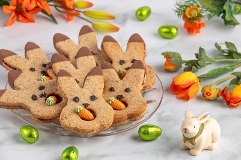 Bunny biscuits with carrots next to orange flowers and Easter bunny