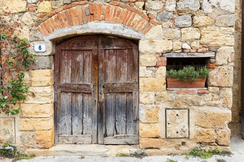 Quarry stone wall with old wooden door and house number 6, rosemary in a flower box, in the