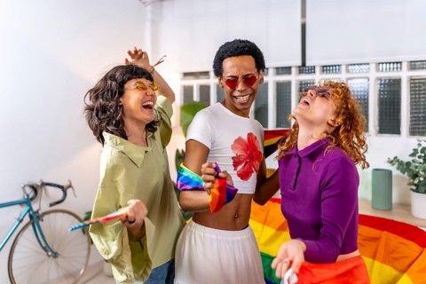 Happy friends celebrating pride party at home dancing and laughing together