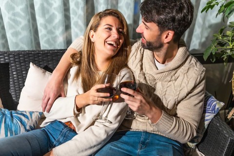 Romantic couple enjoying a relaxing evening together, sharing drinks and laughter on a comfortable