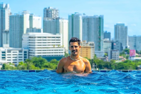 Tourist enjoying refreshing swim in rooftop infinity pool with breathtaking view of cebu city