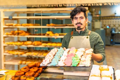 Portrait of a latin male artisan baker showing freshly baked Christmas cookies at shop