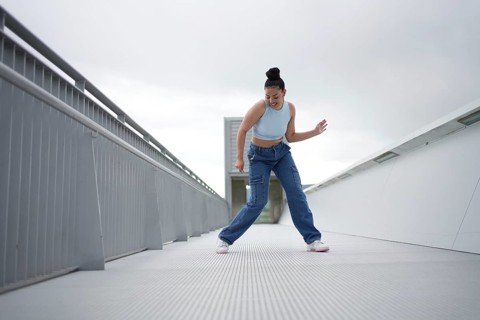 A woman in blue jeans is dancing on a white surface. Concept of freedom and joy as the woman