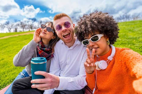 Three cheerful multi ethnic friends making funny faces and gesturing while taking a selfie with