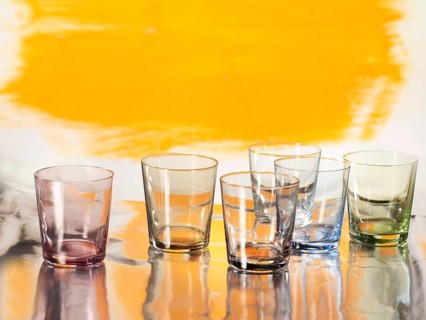 Various glasses on silver foil, yellow coloured surface behind, studio shot