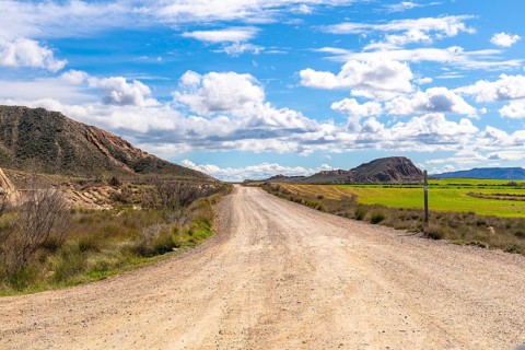 Scenic view of a gravel road stretching through the bardenas reales desert landscape under a bright