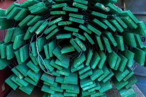 Close-up of rolled fluorescent green painted wood and steel wire snow fence in outdoor storage