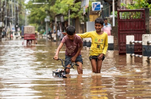 Children wade through a flooded street after heavy rains in Guwahati, India on April 28, 2025