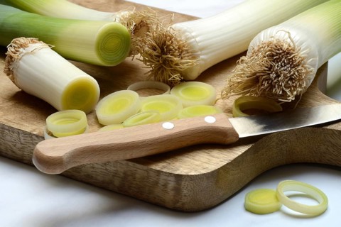 Leek, leek sticks and leek rings on a chopping board with a knife