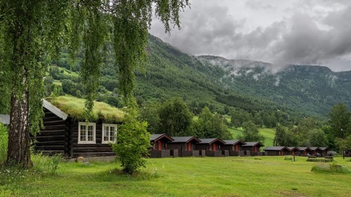 Cloudy forested ridges, wooden huts, Kirketeigen campsite, Kvam, upper Gudbrandsdal, Norway, Europe