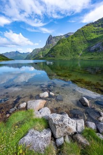 Small boats at the fjord Austnesfjorden, idyllic Norwegian fjord landscape, mountains reflected in