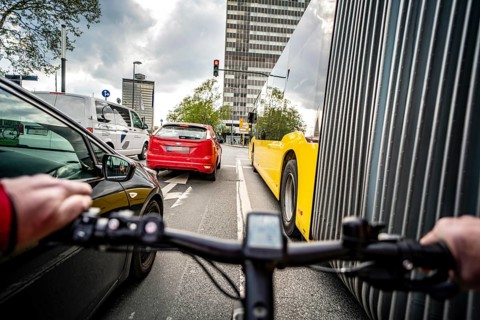 Cycling in the city, city centre road, no cycle path, bus stop, two-lane traffic in both