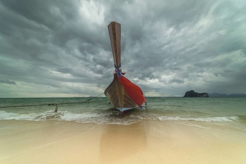 Longtail boat on the beach, dark rain clouds behind, Koh Ngai Island, Andaman Sea, Satun Province,