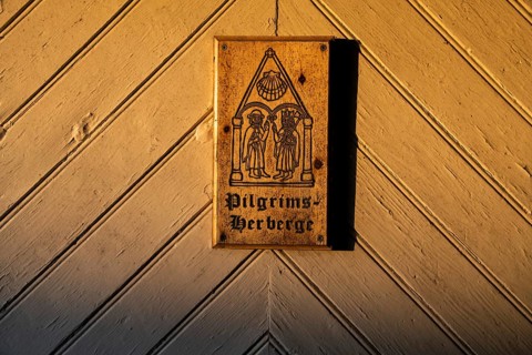 Pilgrims and Olav the Saint or Olav II Haraldsson with axe, Pilgrims Hostel lettering, wooden