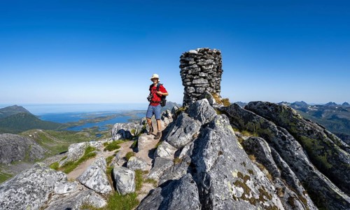 View of mountains and fjord landscape, mountaineer at the summit of Rundfjellet, Svolvaer,