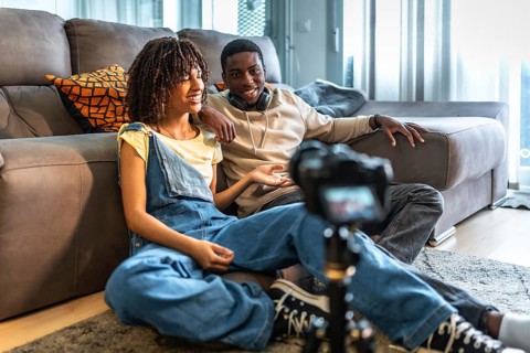 Two videomakers are creating content for their channel, discussing and smiling while recording a