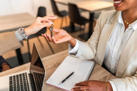 Real estate agent handing over keys to a new homeowner, symbolizing a successful property purchase