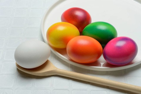 Coloured eggs on a plate and uncoloured eggs on a spoon, Easter celebration