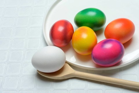 Coloured eggs on a plate and uncoloured eggs on a spoon, Easter celebration