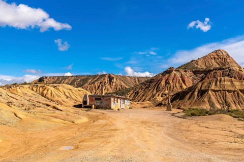 Scenic view of an abandoned, graffiti covered building rising from the arid bardenas reales desert