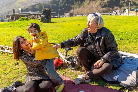 Mother and grandmother having fun with their child in a park, enjoying a sunny day outdoors