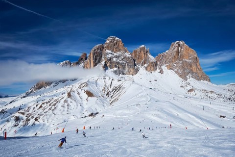 View of a ski resort piste with people skiing in Dolomites in Italy