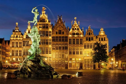 Antwerp famous Brabo statue and fountain on Grote Markt square illuminated at night and old houses.