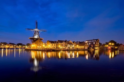View of Harlem cityscape with landmark windmill De Adriaan on Spaarne river in the night