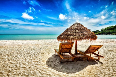 Vacation holidays background wallpaper, two beach lounge chairs under tent on beach. Sihanoukville,