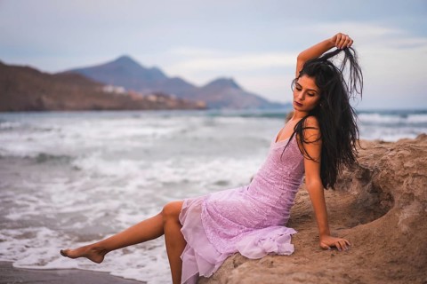 Portrait of a young brunette Caucasian woman in a pink cloth dress, on the beach by the sea in Cabo