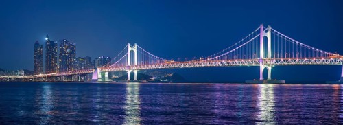 Panorama of Gwangan Bridge and skyscrapers illuminated in the night. Busan, South Korea, Asia