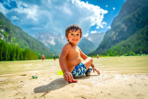 Smiling child playing with a toy car on the shore of lake landro, also called durrensee, in the