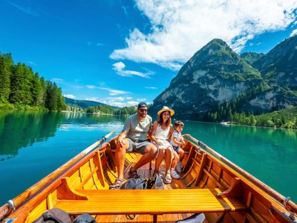 Family enjoying a sunny summer day rowing a wooden boat on the crystal clear waters of lake braies,