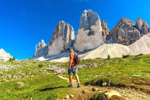 Hiker enjoying the breathtaking view of the tre cime di lavaredo peaks during a sunny summer day in