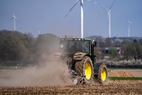 A tractor works a field, due to long dryness in spring, no rain for more than 4 weeks, the fields